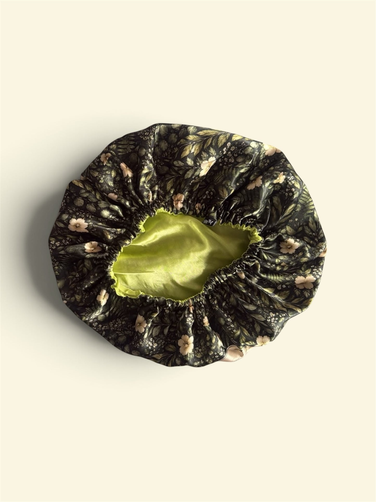 Purrty Dimples satin hair bonnet with dark forest floral print exterior and vibrant lime-green satin lining.